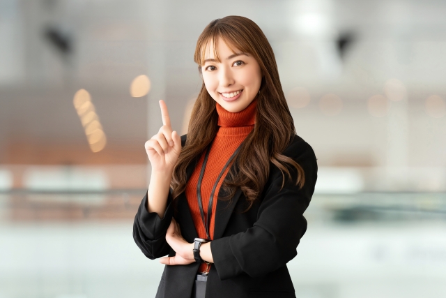 人差し指を立てて案内するビジネスウーマン