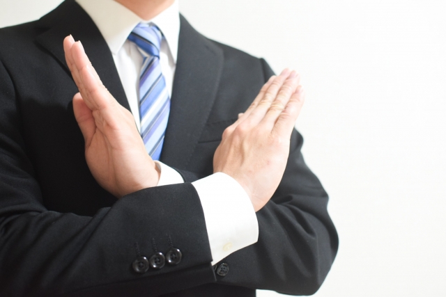 バツマークをするリクルートスーツの男性