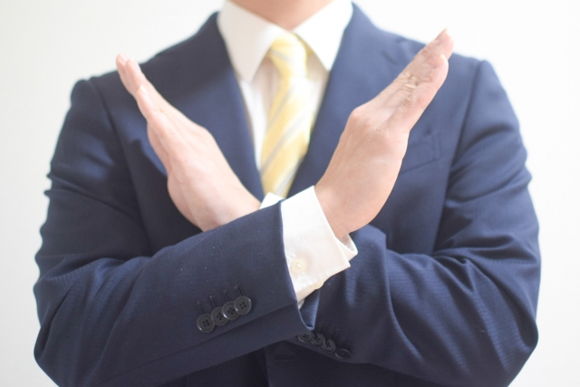 バツマークをするスーツ姿の男性