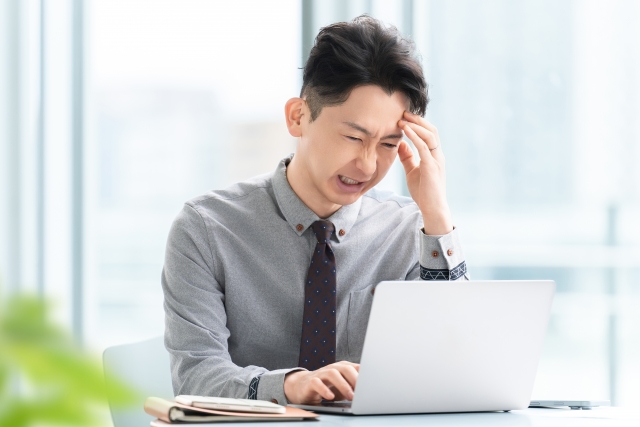 パソコンを使いながら悩む男性ビジネスマン