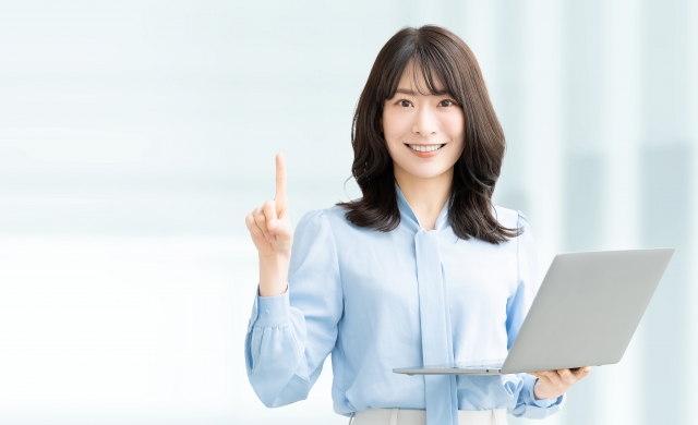 パソコンを持って案内をする笑顔の女性