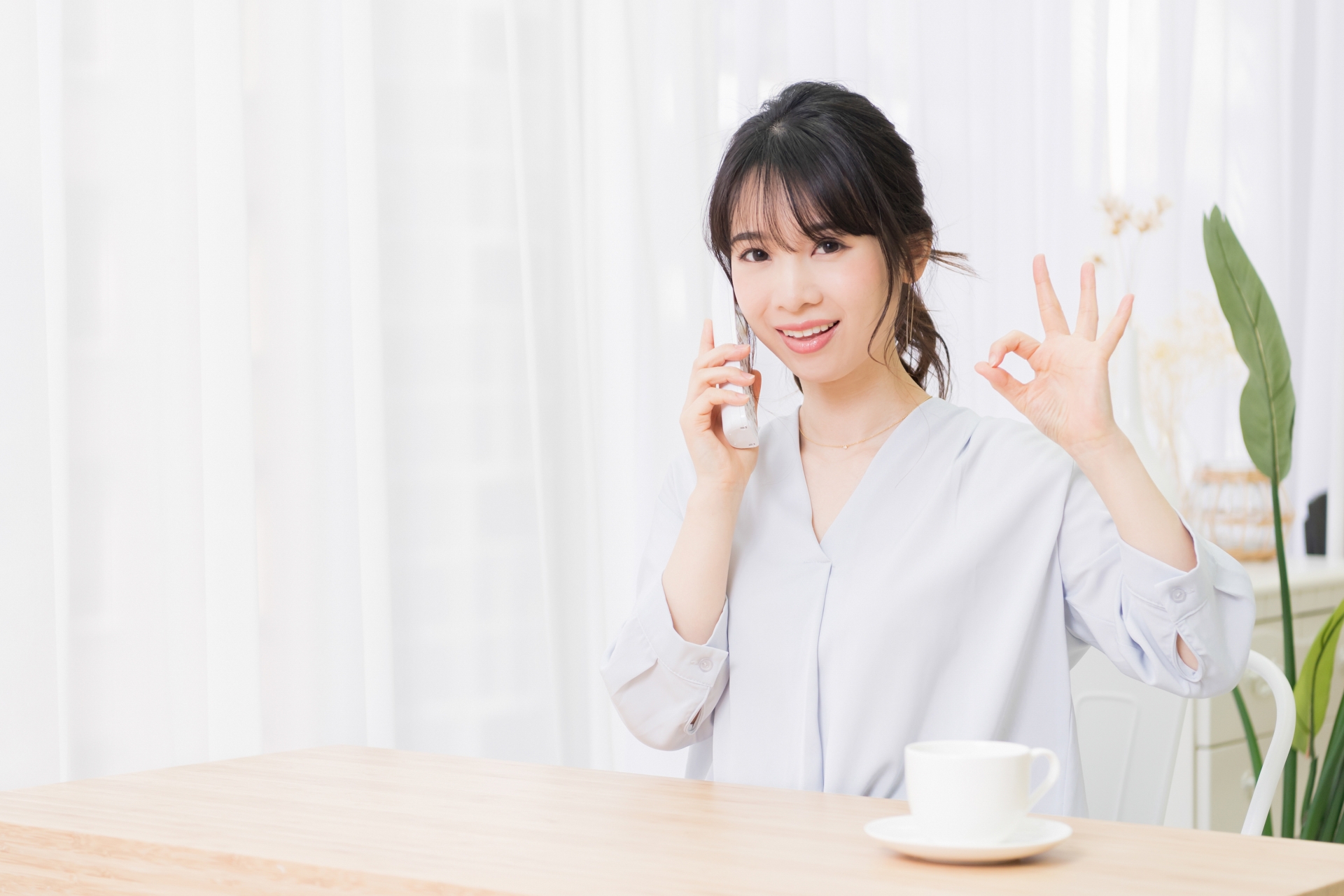電話をしながらOKサインを出す女性